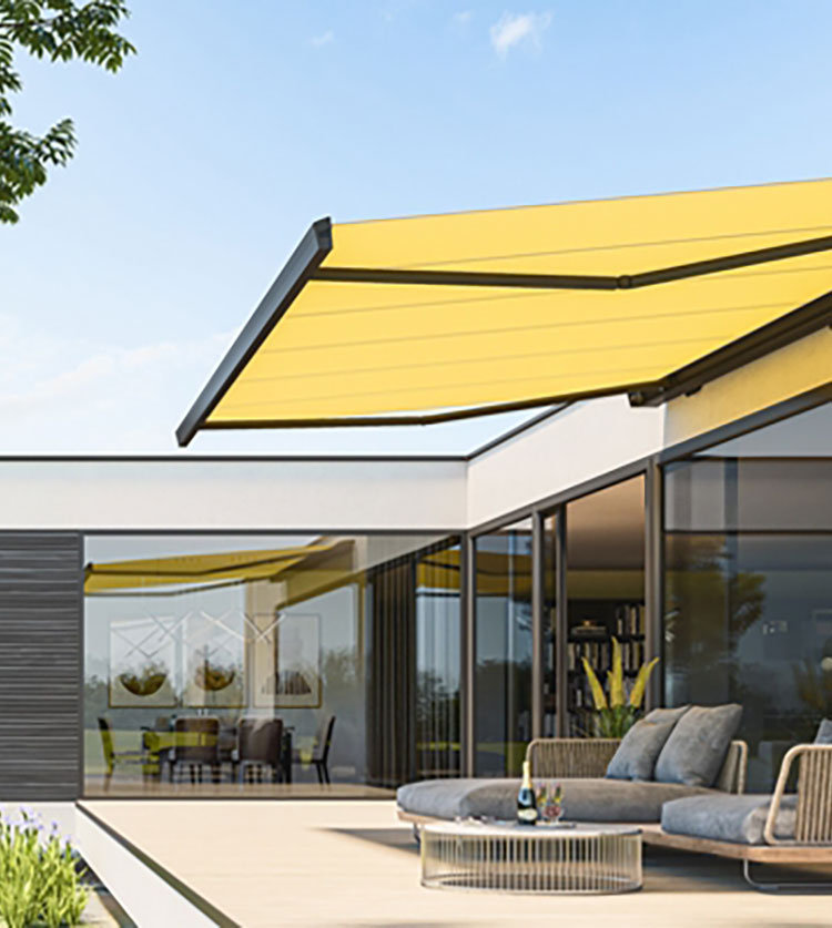 Modern patio with yellow retractable awning extended over outdoor seating area, attached to a glass-walled home.